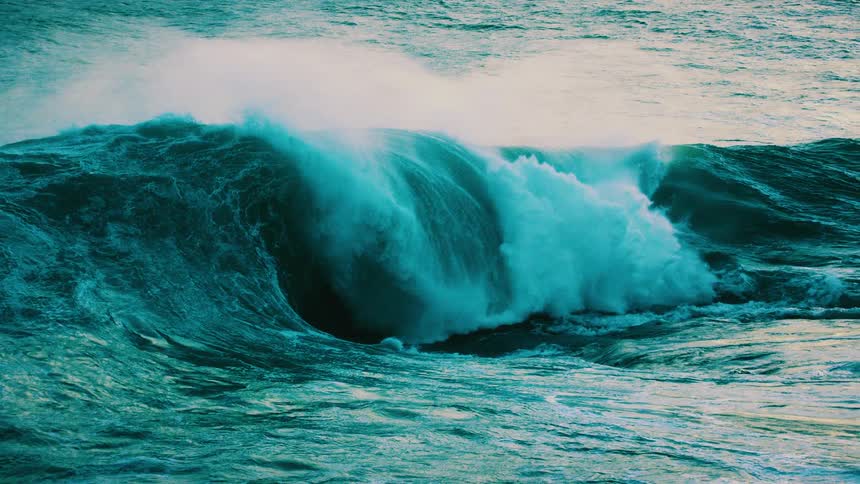 A massive turquoise ocean wave swells and crashes in stunning super slow motion