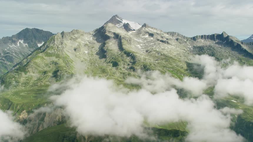Clouds hover below the peaks of a mountain range