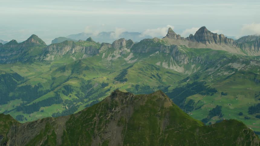 Mountain range covered in green trees and grass on cloudy day
