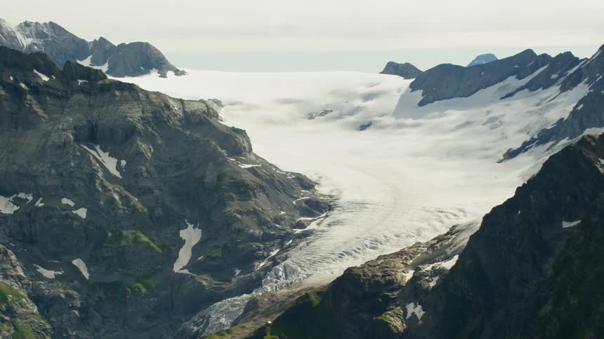 A large glacier rests between mountain peaks
