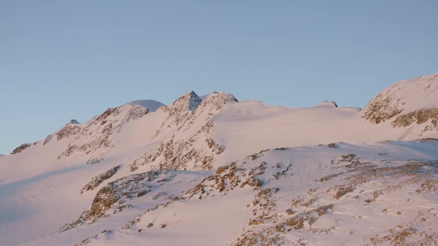 Blue sky over jagged snow covered mountain peaks