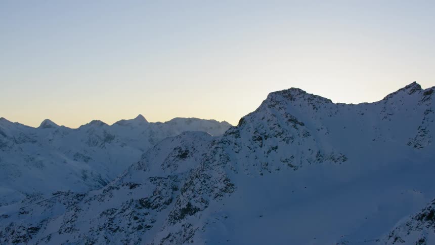 Sunlight shining over peaks of snow covered mountains
