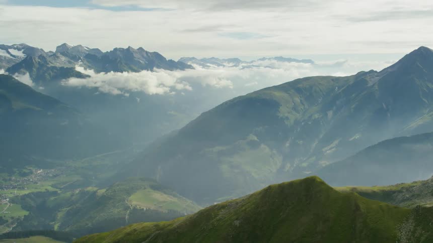The long range of mountains has clouds touching the top