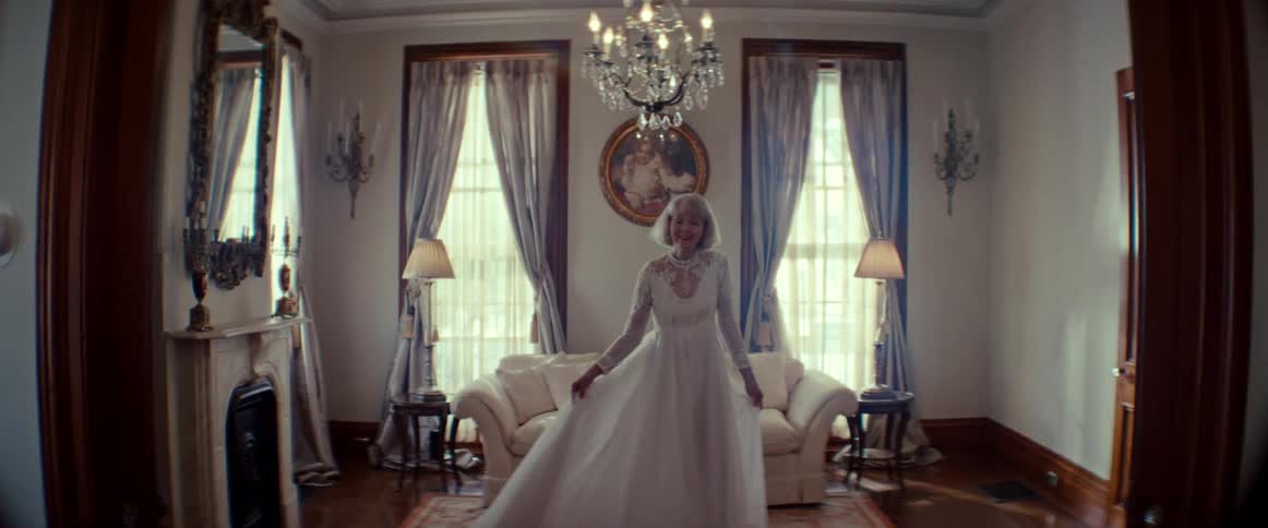 A graceful senior bride in a beautiful white wedding dress twirls slowly and smiles with pure joy in an elegant living room