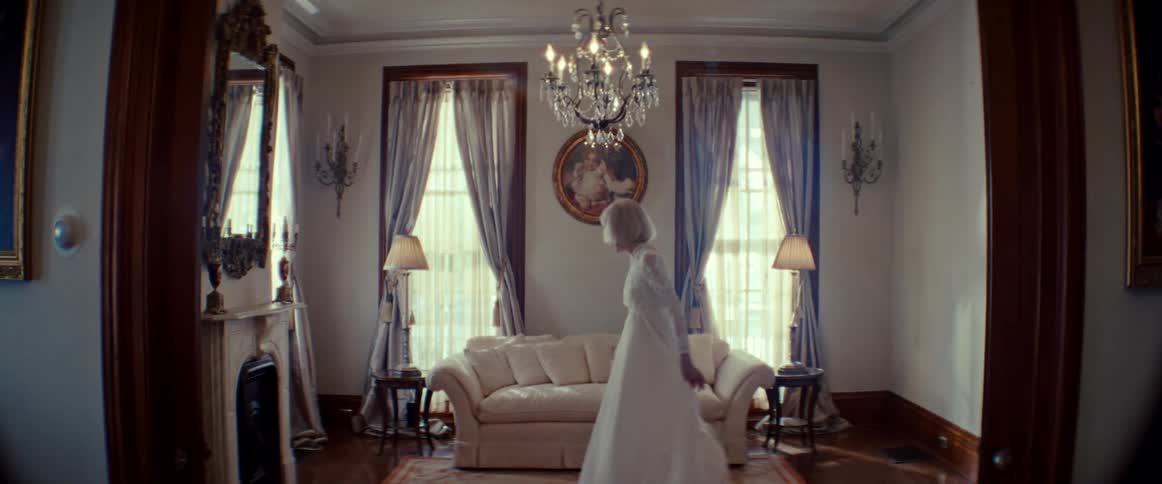 An elegant bride happily twirls in her beautiful wedding dress inside a classic sunlit room
