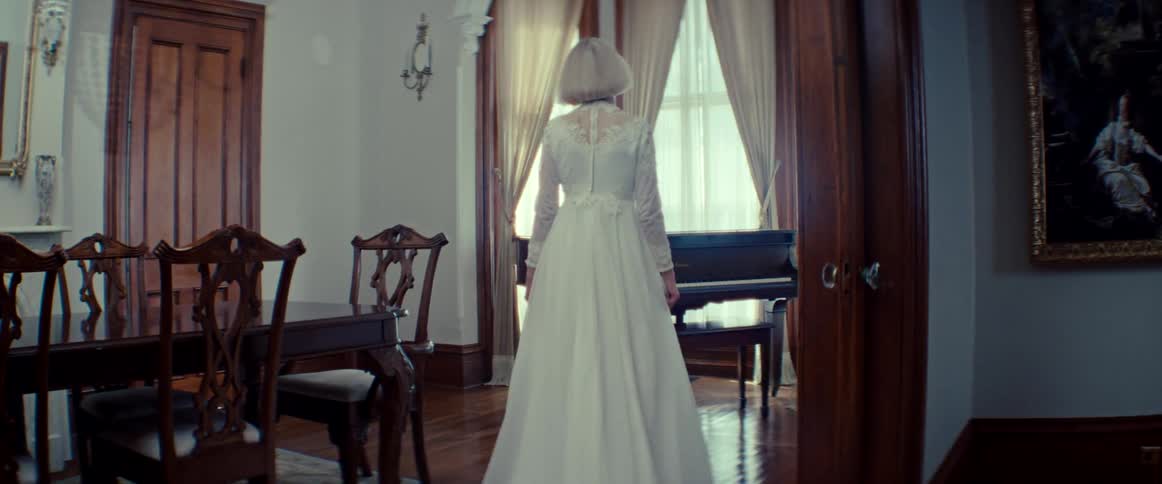 A mysterious bride in a vintage white gown slowly approaches a grand piano in a stately, sunlit room
