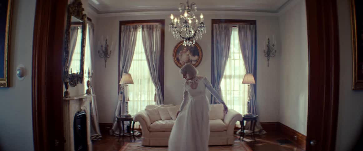 A ghostly figure of a bride in a white gown slowly dances in a grand, vintage living room