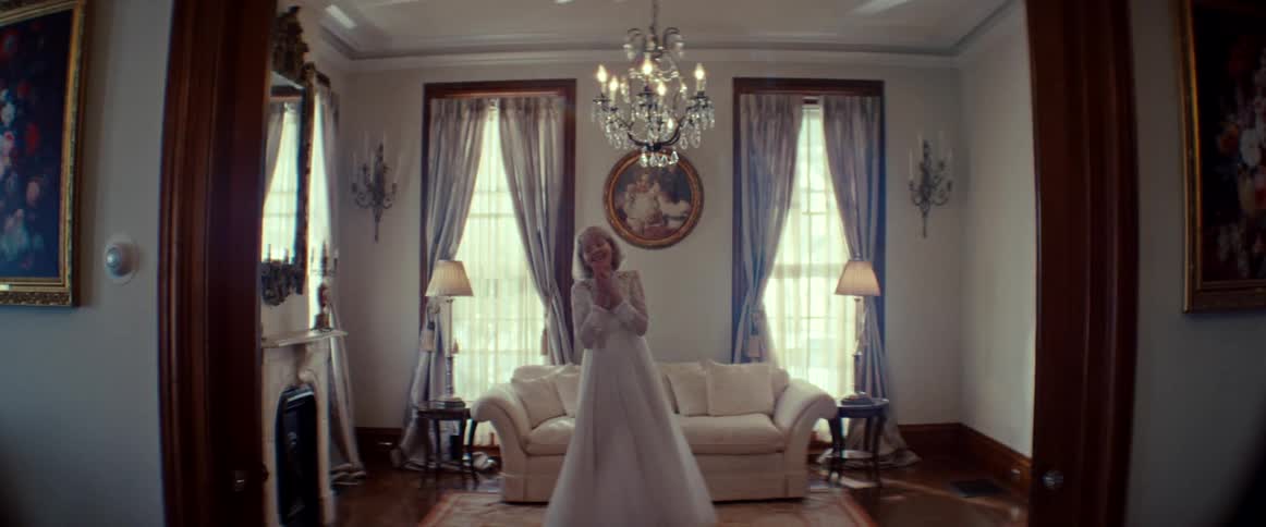 A ghostly woman in a vintage wedding dress dances slowly in an ornate, old-fashioned living room