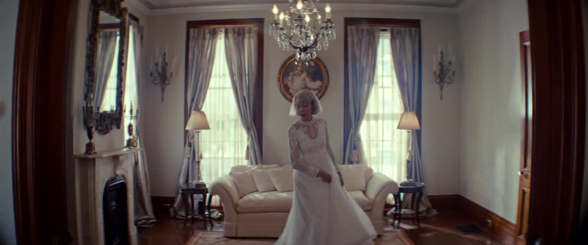 A graceful senior woman smiles as she slowly twirls in her vintage wedding dress inside an elegant living room