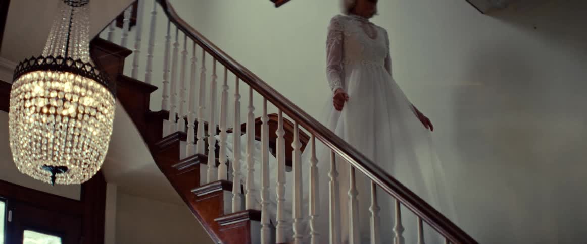 A beautiful senior bride stands at the top of a grand staircase, smiling warmly