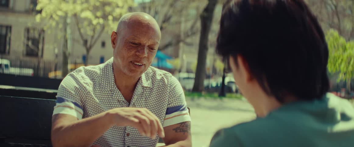An older man thoughtfully makes his move while playing a board game with a friend in the park on a sunny day