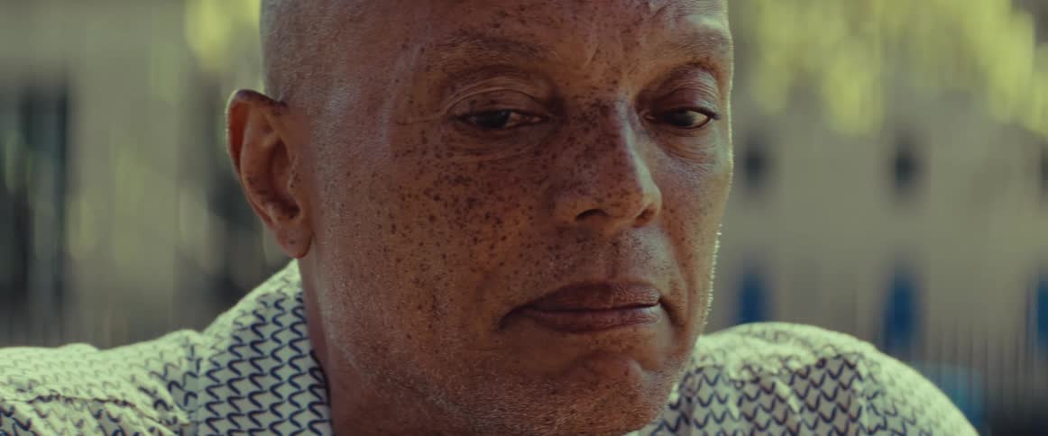 A thoughtful older Black man with a pensive expression looks down in a cinematic close-up