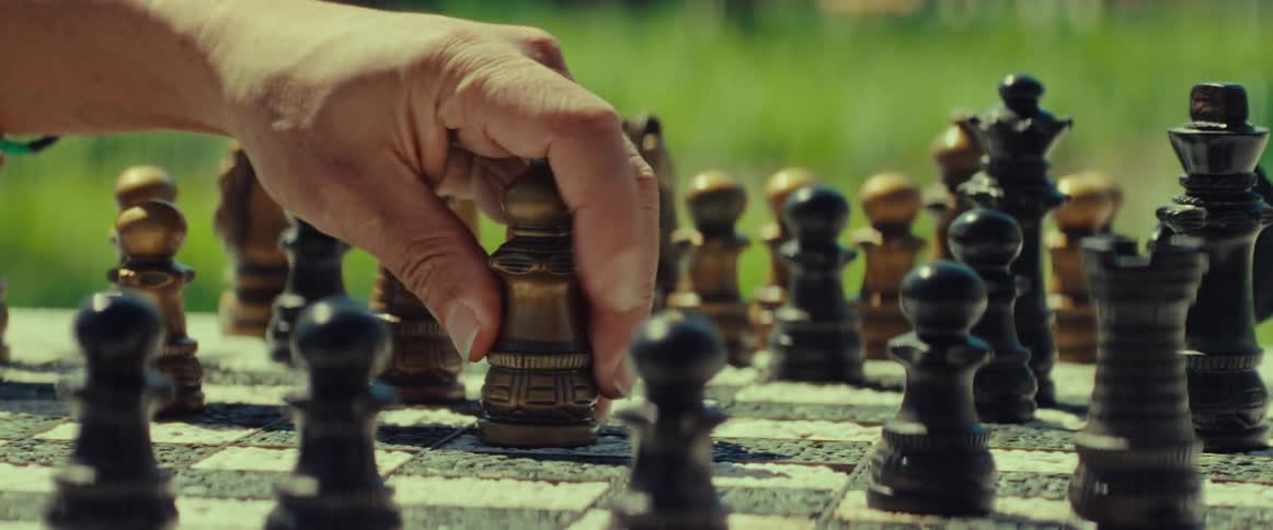 A strategic move is made with a bishop during an outdoor chess match on a sunny day