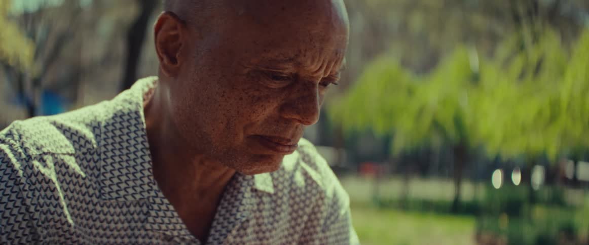 Slow-motion close-up of a thoughtful elderly Black man concentrating on moving a chess piece during a game in the park