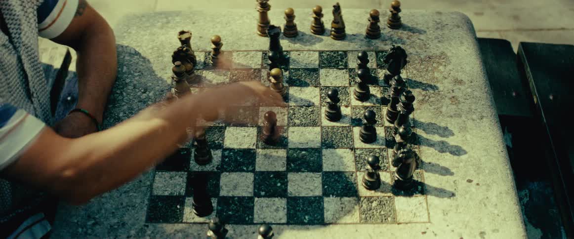 A time-lapse view from above shows a fast-paced chess game being played on a weathered stone table