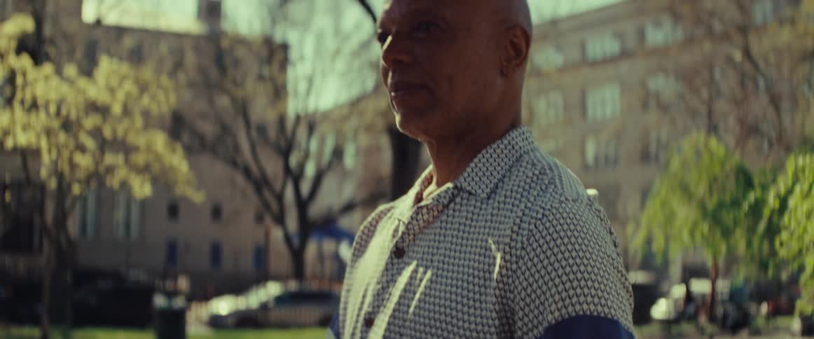 Close-up reveals a senior man holding a chessboard as he contemplates in an urban park on a sunny day
