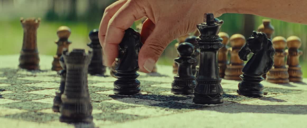 A player makes a move with the black knight piece during an outdoor game of chess in the park
