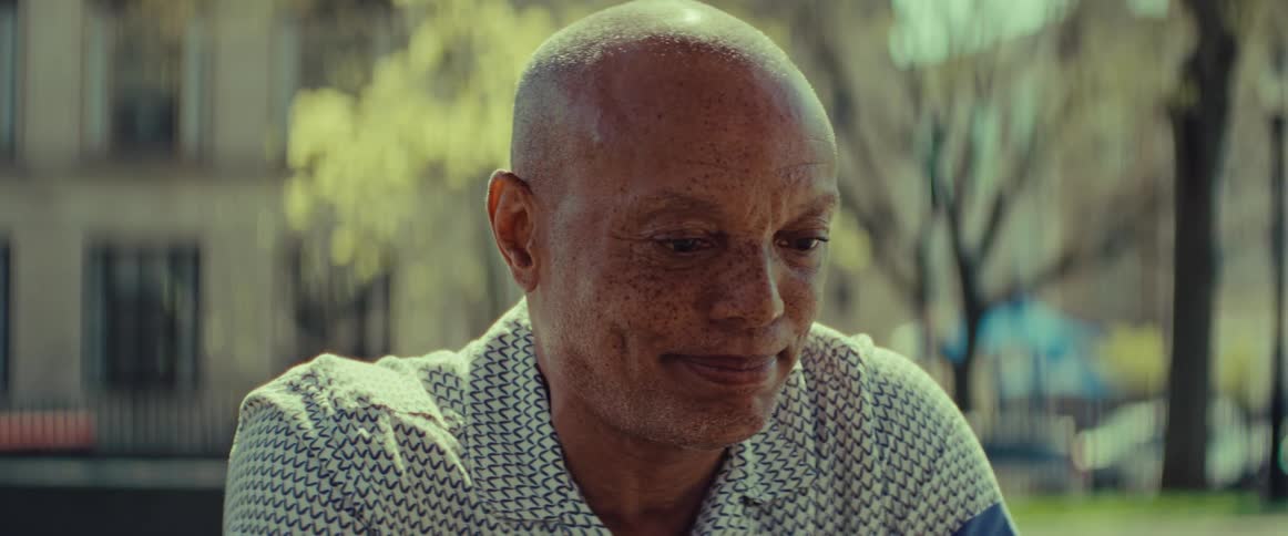Close-up portrait of a thoughtful older man sitting pensively in a park on a sunny day