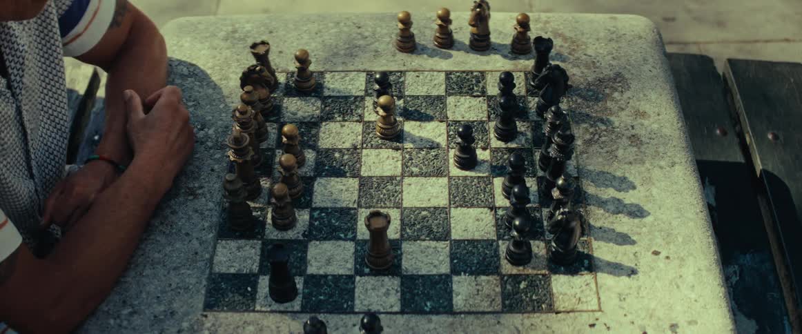 An overhead time-lapse shows a fast-paced game of chess unfolding on a weathered stone board