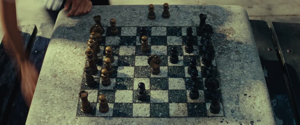 An overhead shot of two people playing a strategic game of chess on an outdoor stone table