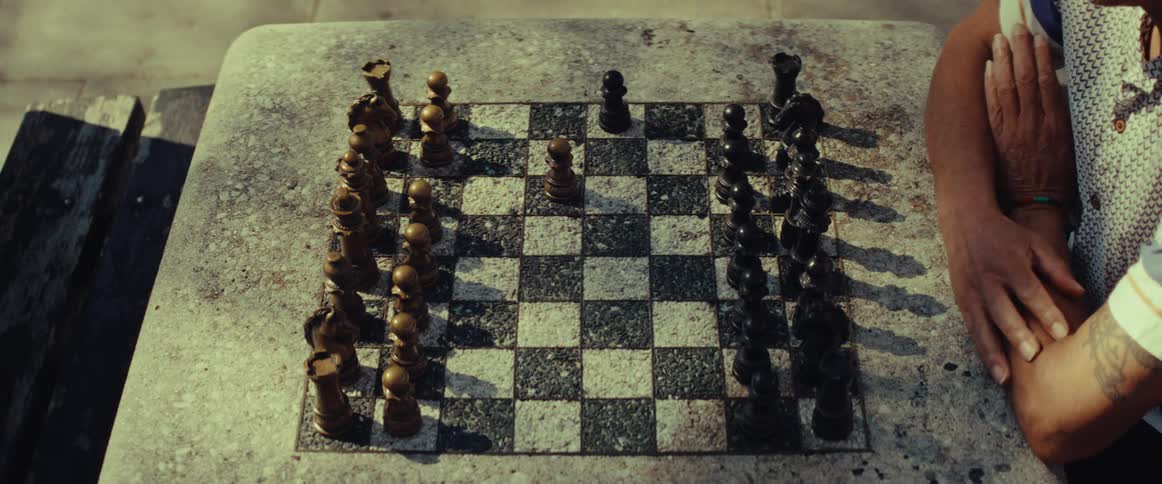 A top-down view captures the strategic opening moves of a chess game played on a rustic stone board