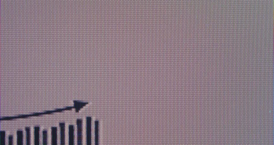 Extreme close-up on a pixelated screen shows a bar graph and arrow rising to represent business success and economic growth