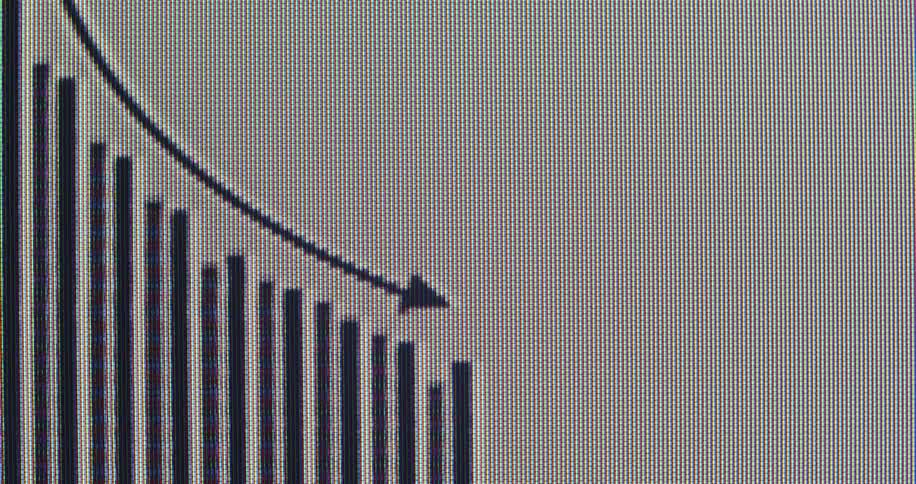 Extreme close-up of a digital screen displaying a bar graph with a downward-trending arrow, indicating a financial decline or market crash