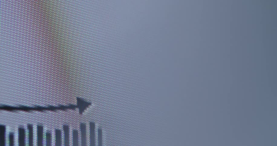 An animated bar graph with a rising arrow appears on a digital screen in this macro shot, symbolizing positive business statistics and financial growth