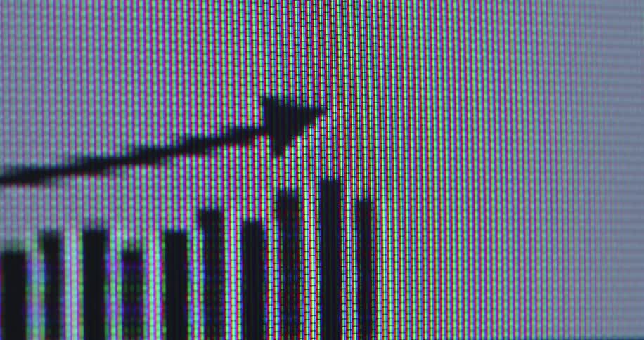 Extreme close-up macro view of a pixelated digital graph with an arrow trending upwards on a screen