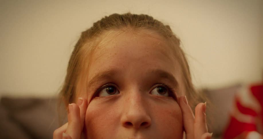 A young girl with braided hair makes a funny face by pulling down on her eyes in slow motion