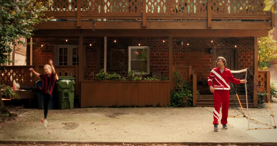 A talented young girl shows off an impressive slow-motion soccer kick to her dad in their urban backyard