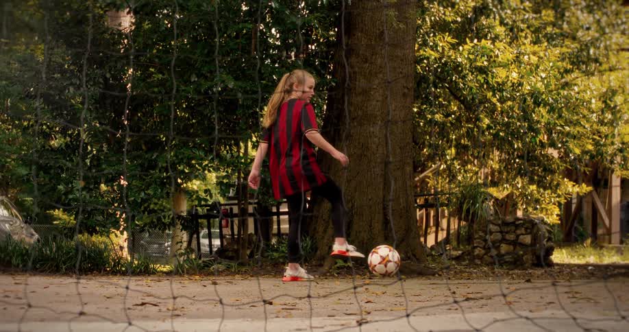 Slow motion shot of a young girl in a soccer jersey skillfully trapping a soccer ball with her foot and smiling confidently