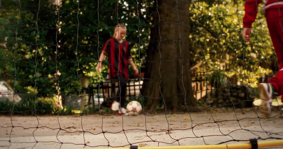 A slow motion close-up of soccer footwork drills transitions to a young girl who scores a goal against the net