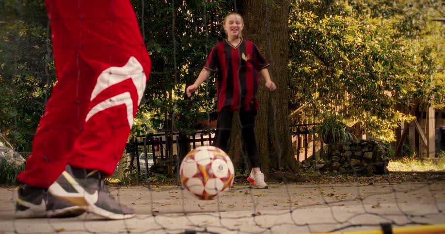 A father and daughter have fun playing footvolley in the park, shot in super slow motion