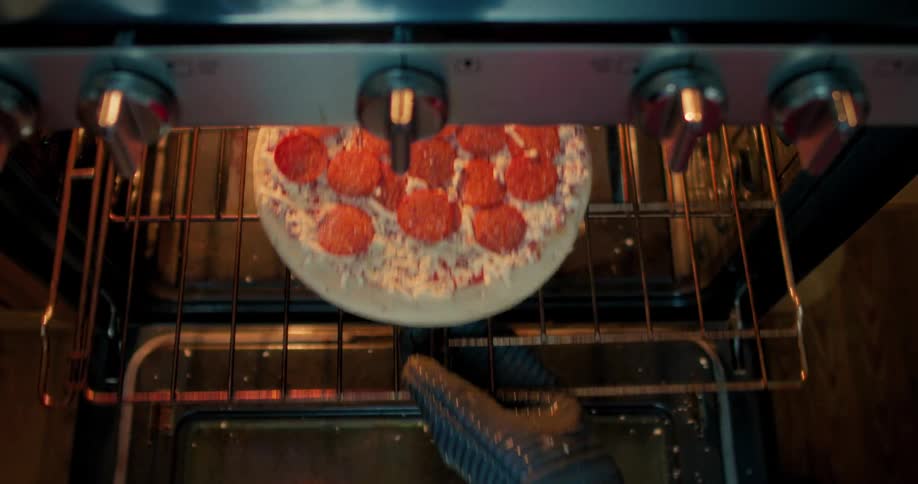 A top-down view shows a hand placing a frozen pepperoni pizza into a preheated oven to cook
