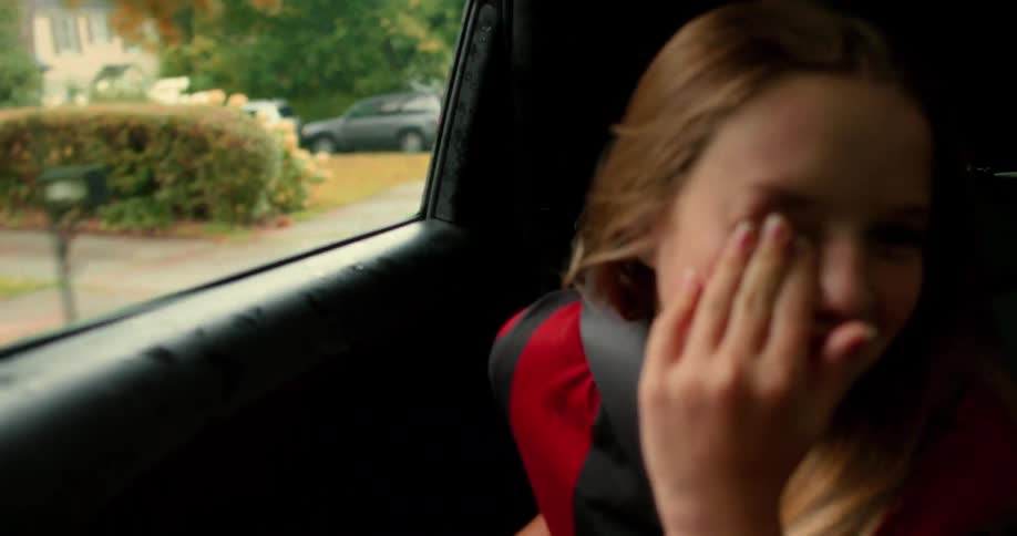 Slow motion shot of a young girl laughing hysterically while riding in the back of a car
