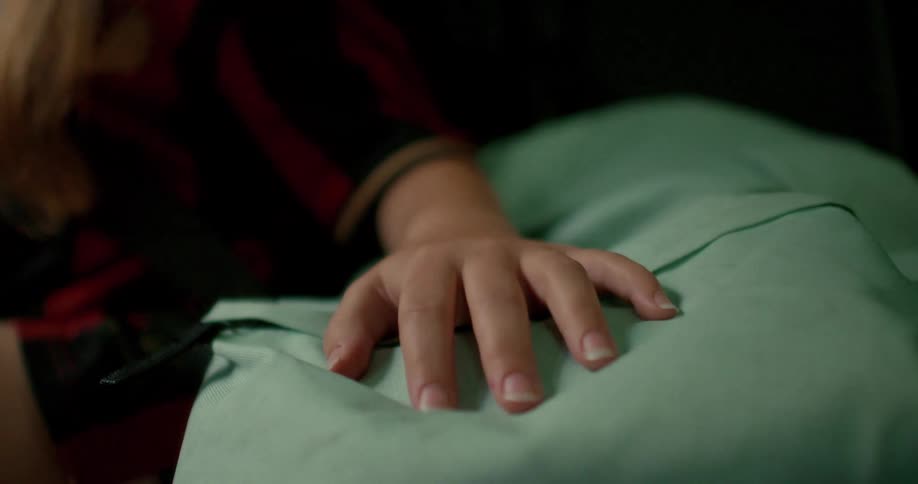 Close-up shot of a woman's hand resting on a green travel pillow while she sits in a moving vehicle