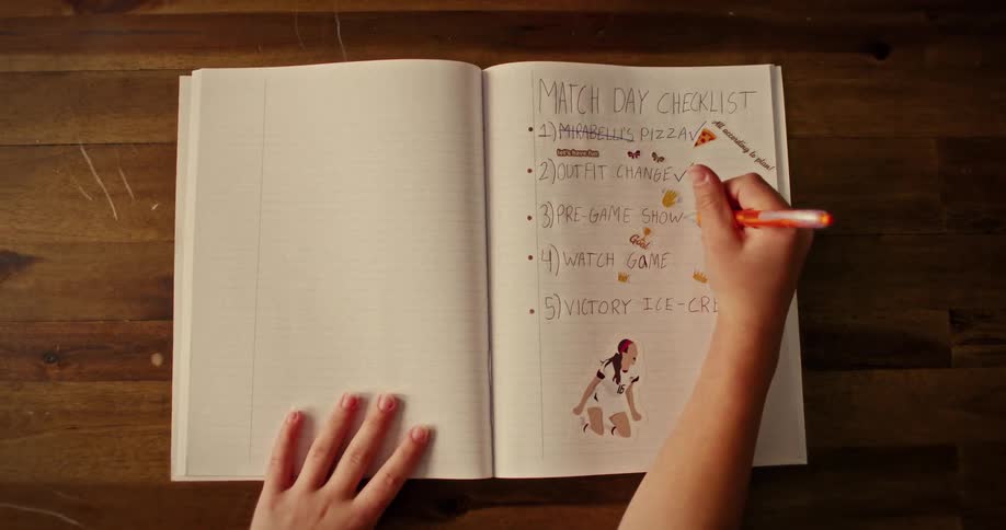 A dedicated sports fan completes their handwritten 'Match Day Checklist' in a notebook adorned with fun stickers