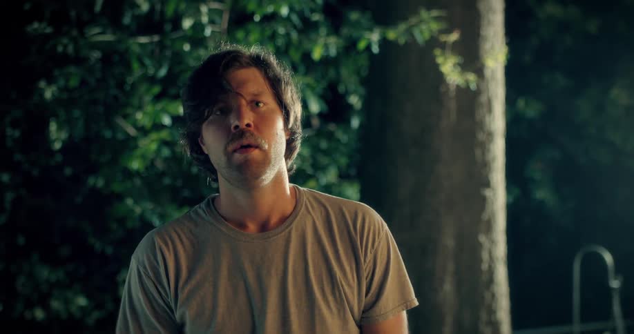 A worried man stretches and tries to compose himself outdoors at night