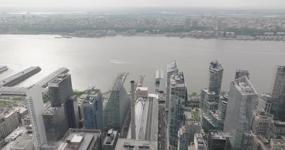 Slow aerial shot pushing in over the modern skyscrapers of Manhattan's west side towards the Hudson River on a hazy day