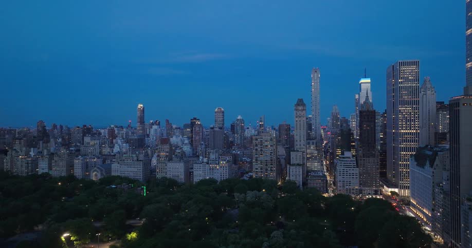 A serene aerial view of the iconic Manhattan skyline over Central Park at dusk as the city lights begin to glow