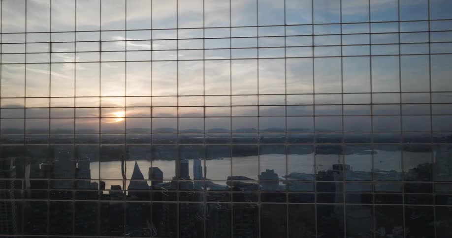 Abstract time-lapse footage captures the city skyline and sunset reflected in the glass windows of a modern skyscraper