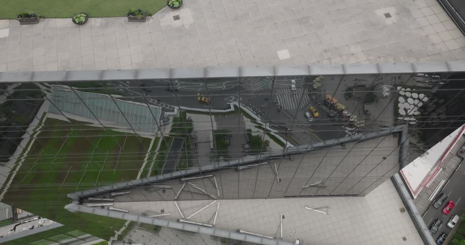 An aerial view of Columbus Circle reflected in the glass facade of a modern skyscraper in New York City as the camera slowly pulls back