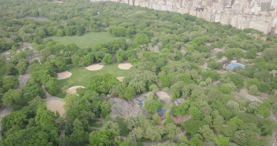 An aerial view flies over the southern end of Central Park, starting at Columbus Circle and tilting up to reveal the iconic Manhattan skyline