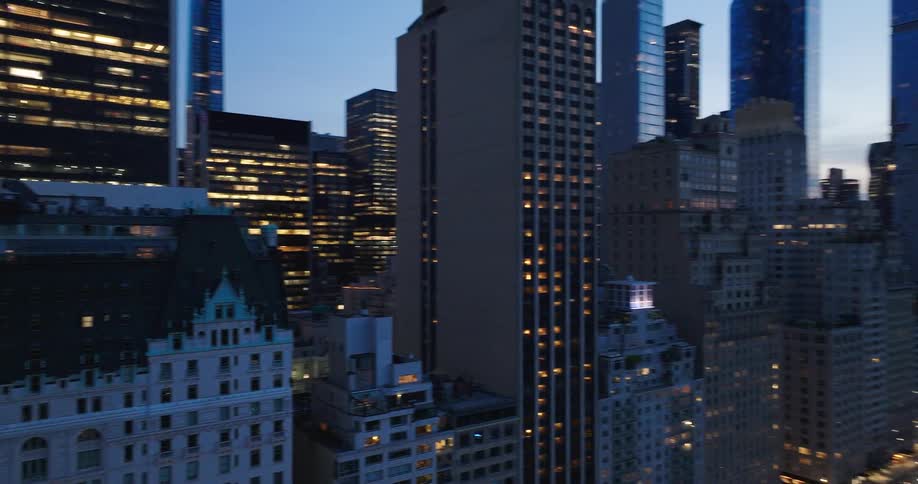 A panoramic aerial view of the iconic Midtown Manhattan skyline and Central Park as the city lights begin to illuminate the evening sky
