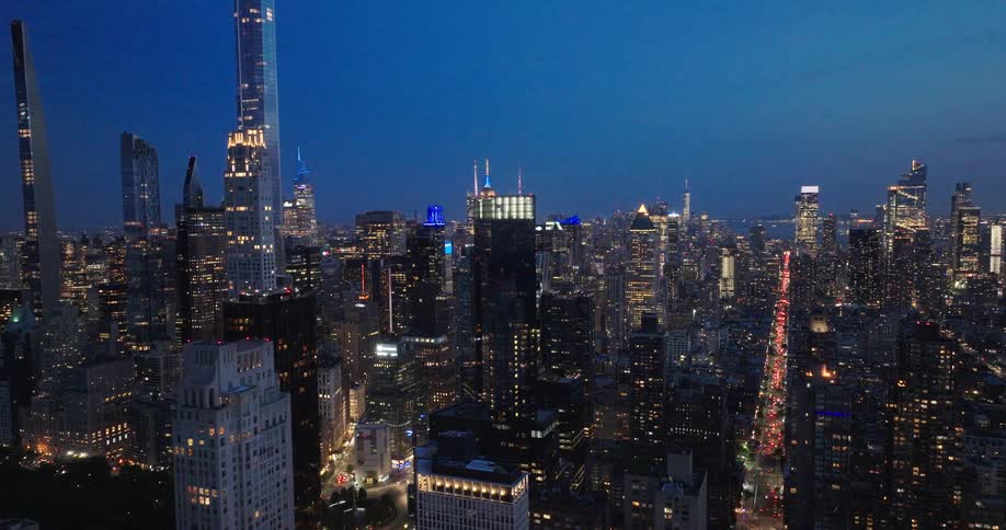 An epic aerial push-in shot over the brilliantly lit Manhattan skyline at dusk