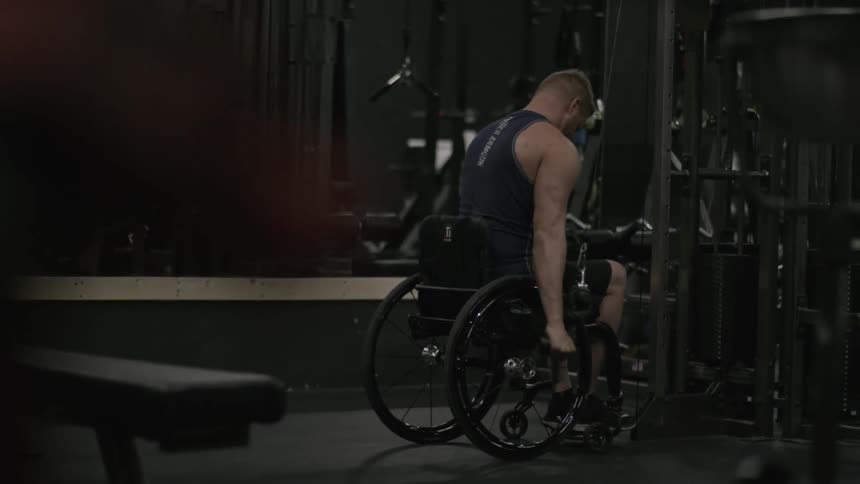 Man in wheelchair working out his arm in gym