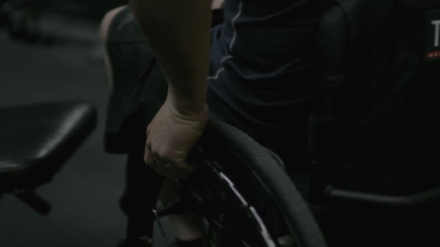 A man in a wheelchair adjusts in his seat