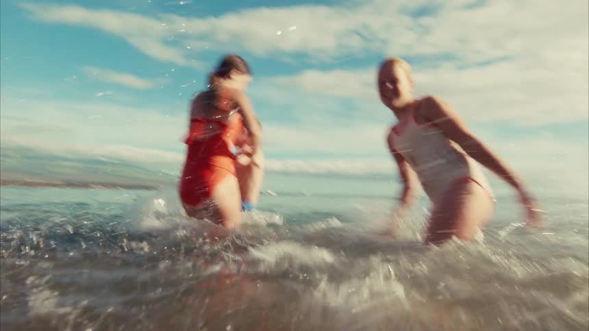 From a water-level perspective, a happy family splashes each other while playing in the sunlit ocean