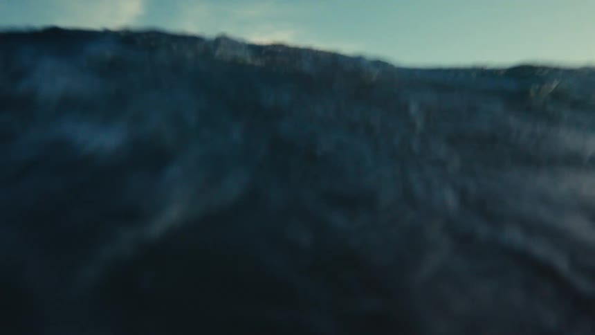 A chaotic point-of-view shot of being tossed by dark ocean waves, submerging and re-emerging from the water